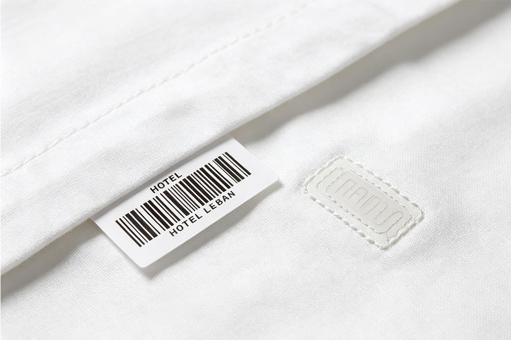 Barcode label and RFID laundry tag attached to textile fabric