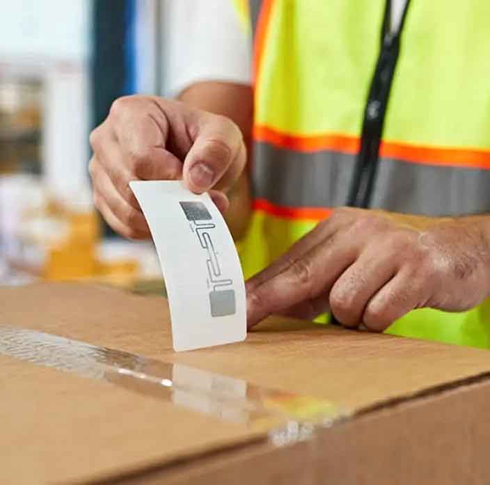 What Is Meant by RFID Tag? 1 Worker attaching an RFID tag label to a cardboard carton in a European warehouse